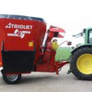 foringsmaskin med halmblåser bak en grønn traktor sett fra siden